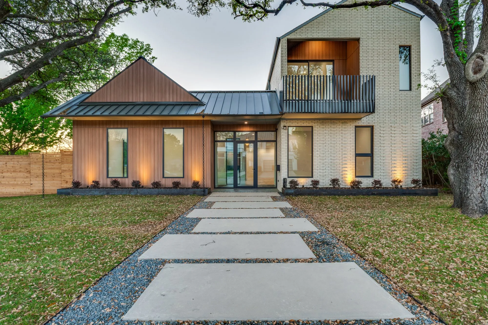 4103 Saranac: front of the house at dusk, with wood siding, pale brick and a dark metal roof