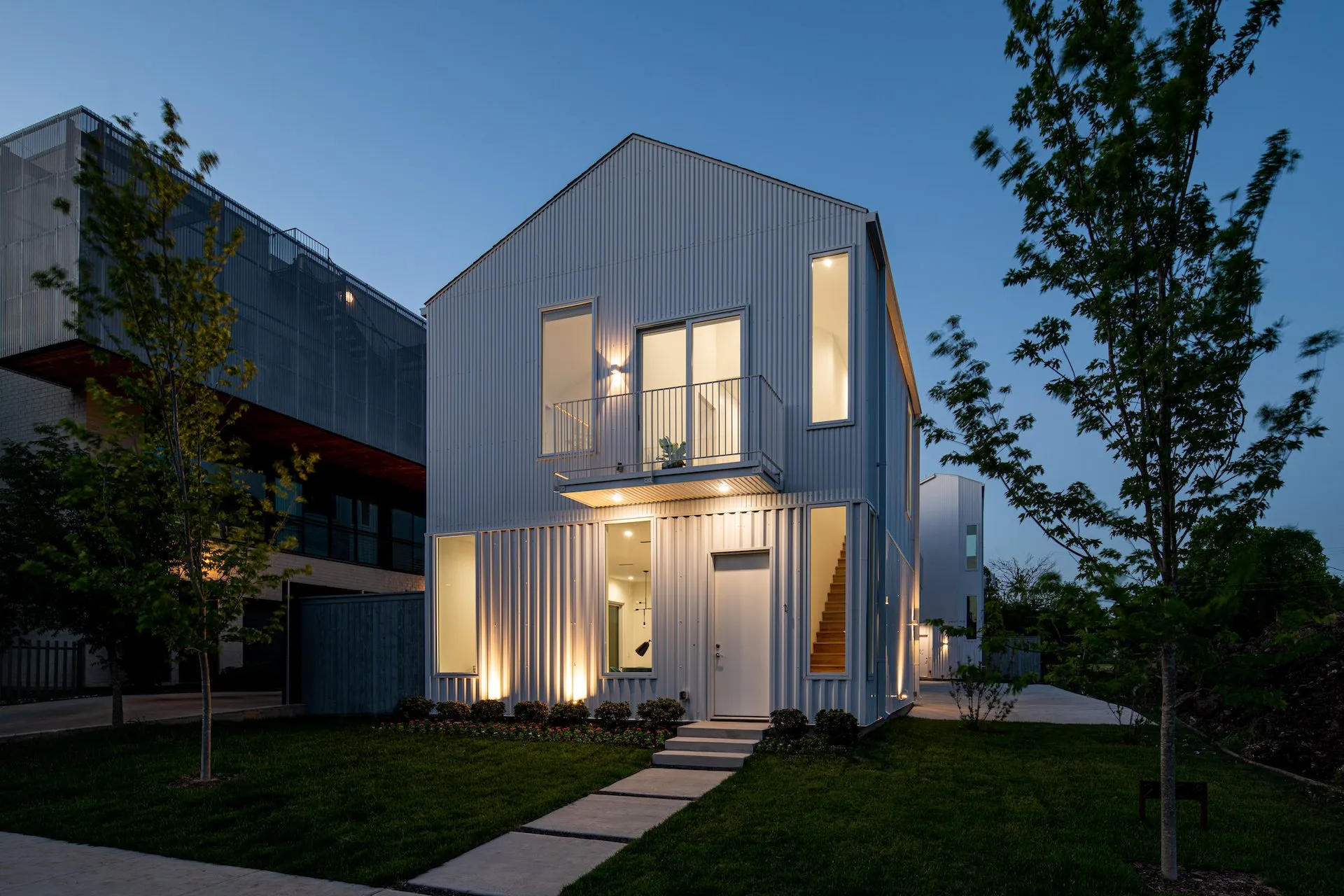 2208 Moser Avenue at dusk, a white metal-clad house with a balcony