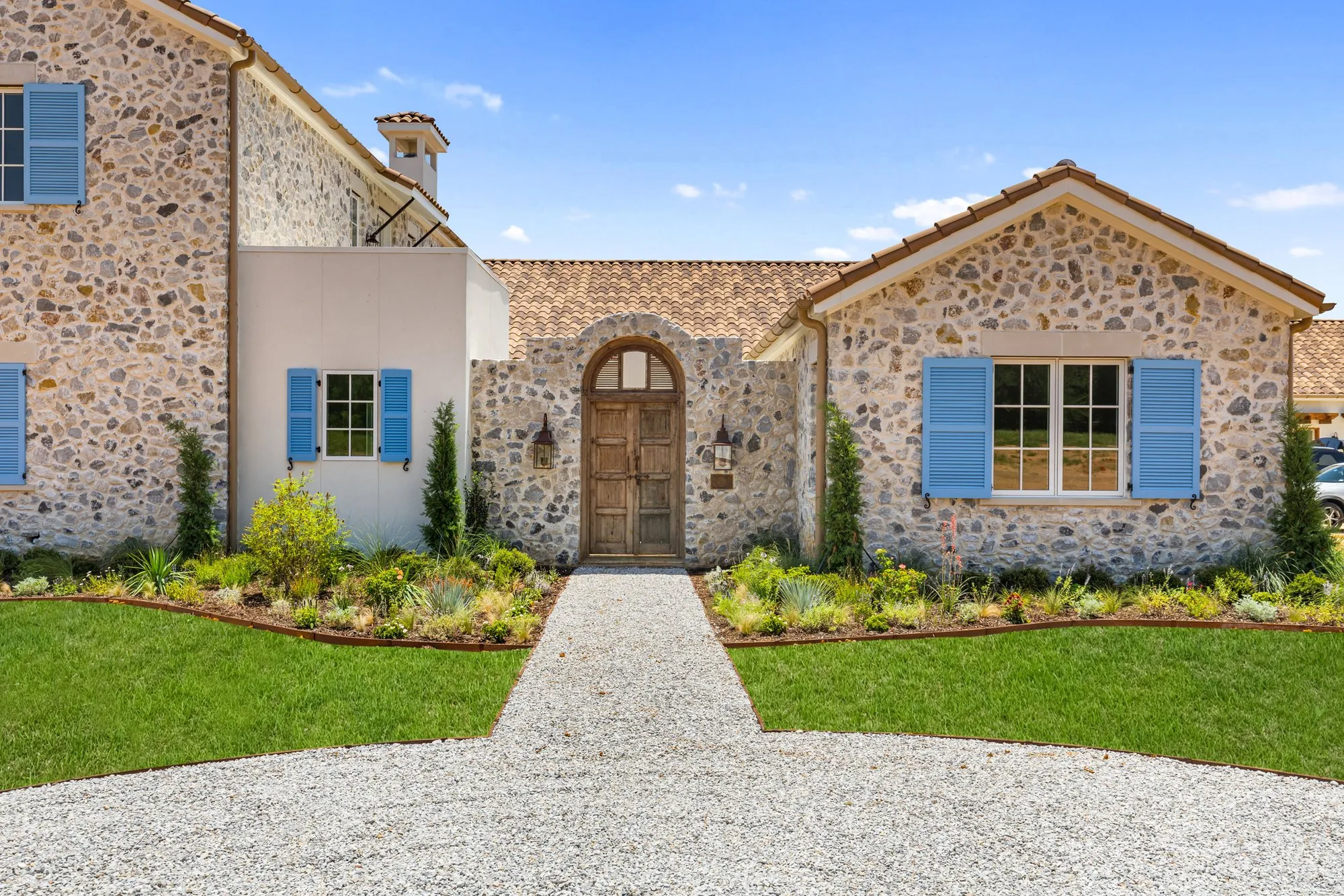 721 Eagles Landing, a stone house with blue shutters and an arched wood door